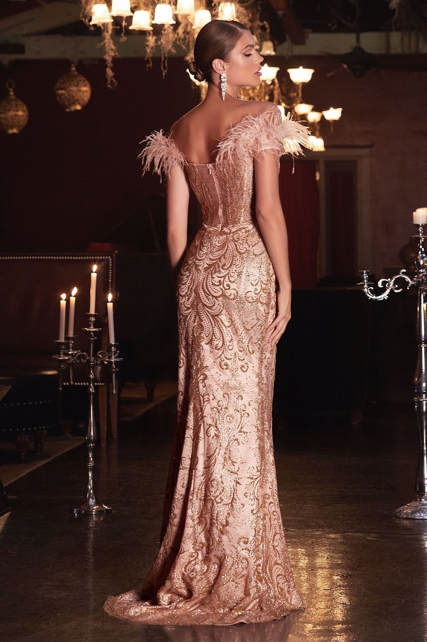 A back view of a mermaid gown with a sheer covered back and feathered off-the-shoulder detail.