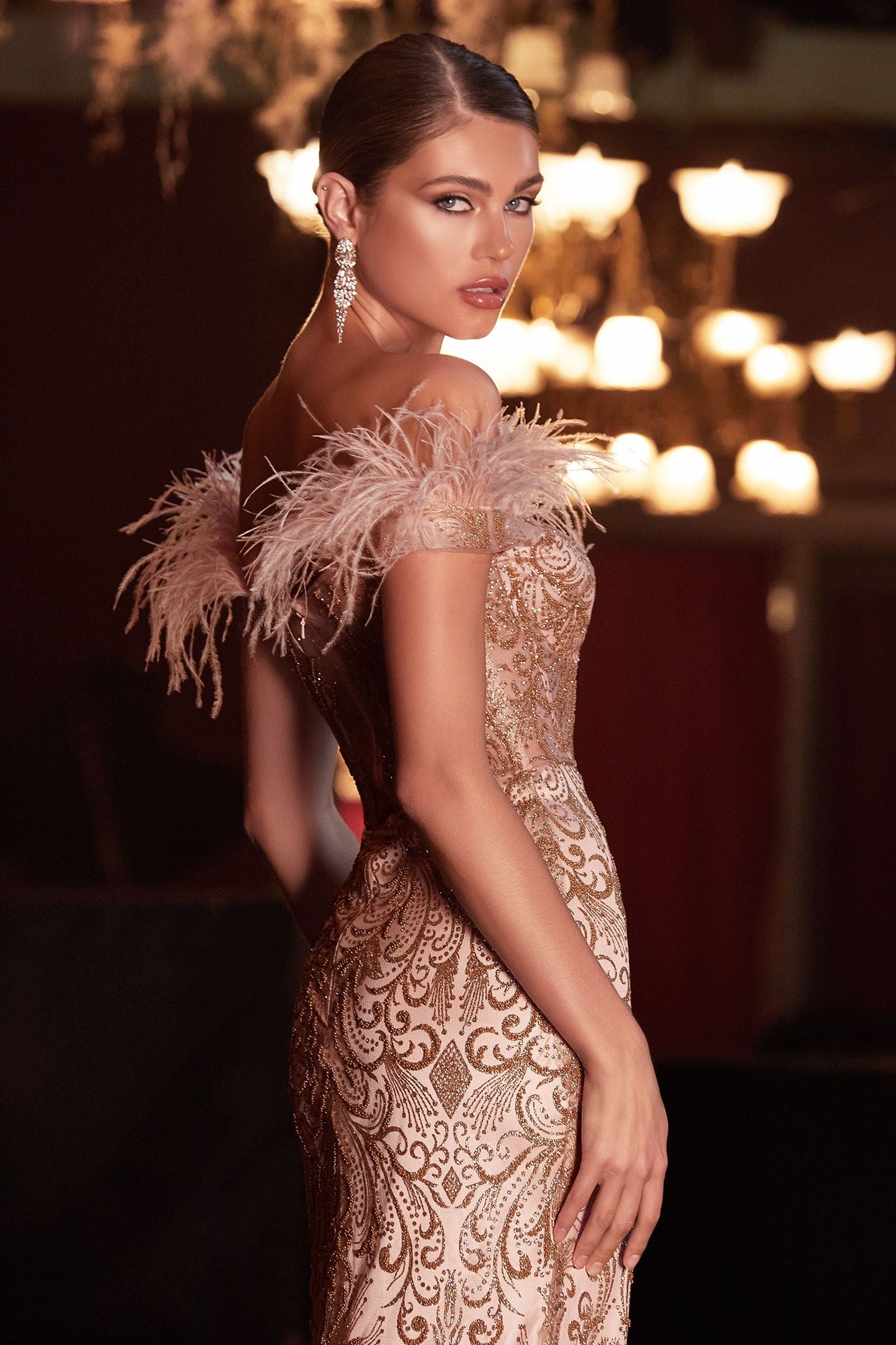 A back view of a mermaid gown with a sheer covered back and feathered off-the-shoulder detail.