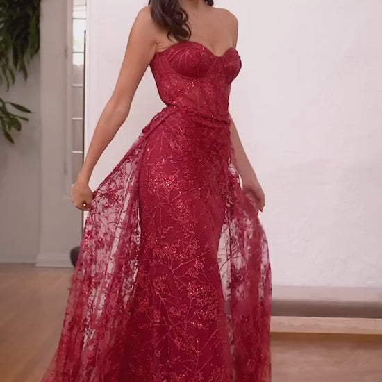 Sultry strapless mermaid gown with a dramatic overskirt for added allure.