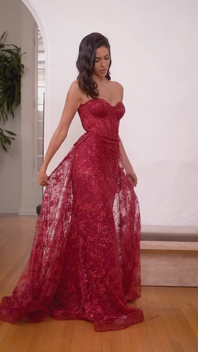 Sultry strapless mermaid gown with a dramatic overskirt for added allure.